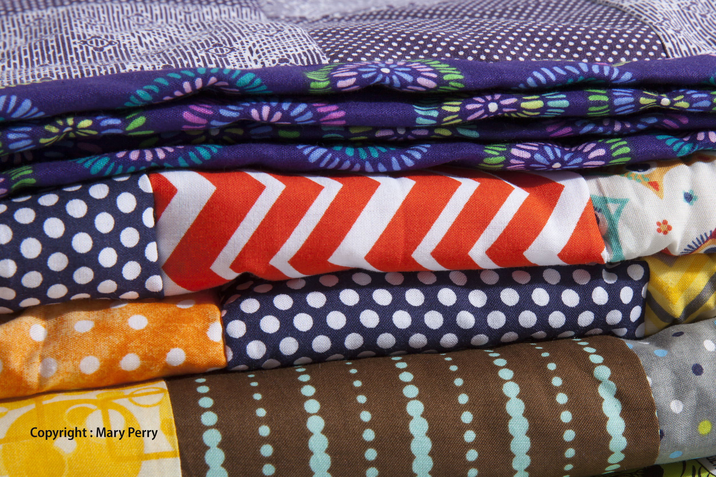 39550917 - a close up of stacked quilts showing different patterns and cloth texture.